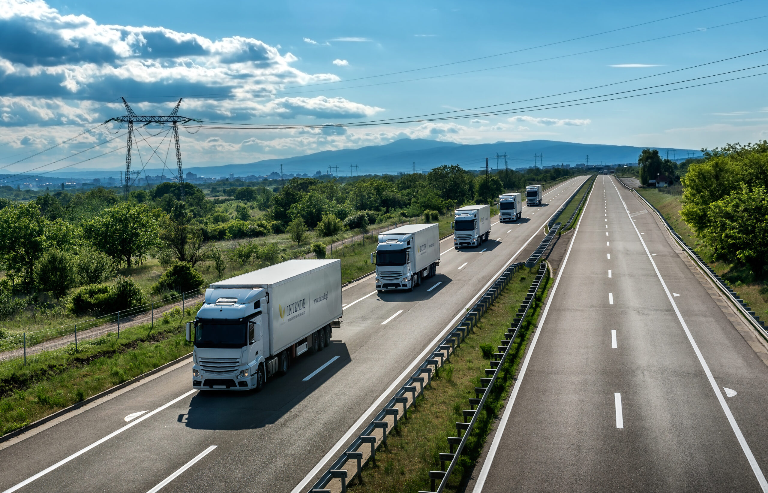 Fleet or Convoy of big transportation trucks in line  on a countryside highway under a blue sky